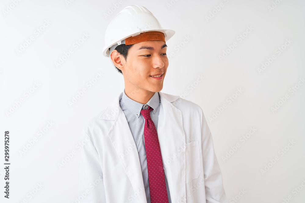 Chinese architect man wearing coat and helmet standing over isolated white background looking away to side with smile on face, natural expression. Laughing confident. Chinese architect man wearing coat and helmet standing over isolated white background looking away to side with smile on face, natural expression. Laughing confident.