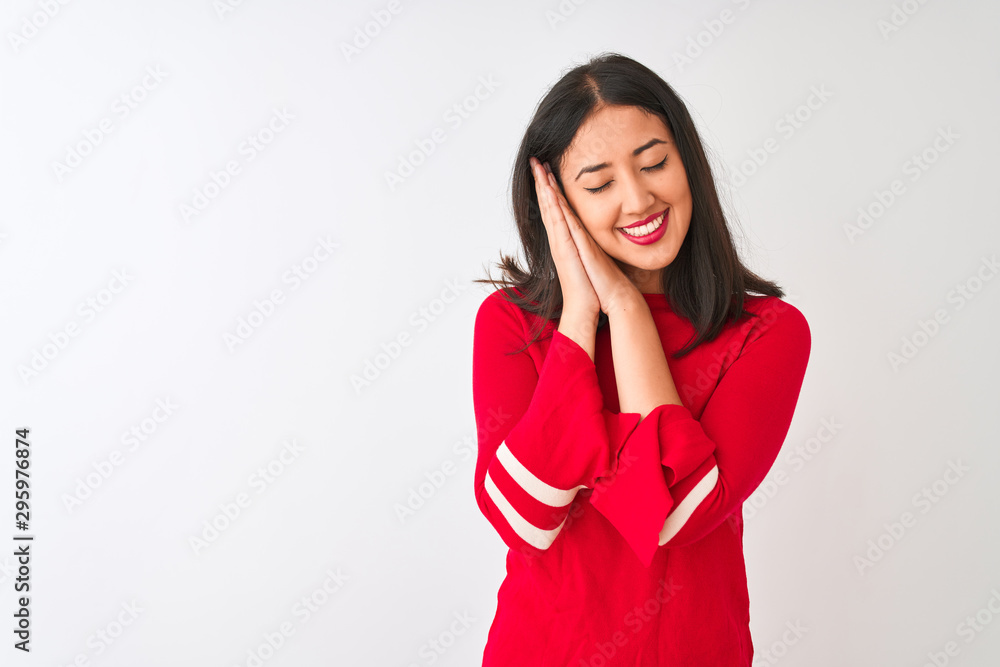 Young beautiful chinese woman wearing red dress standing over isolated white background sleeping tired dreaming and posing with hands together while smiling with closed eyes. Young beautiful chinese woman wearing red dress standing over isolated white background sleeping tired dreaming and posing with hands together while smiling with closed eyes.