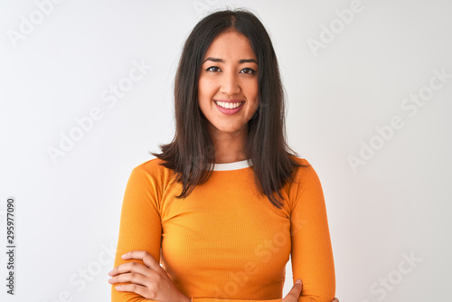 Young beautiful chinese woman wearing orange t-shirt standing over isolated white background happy face smiling with crossed arms looking at the camera. Positive person.
