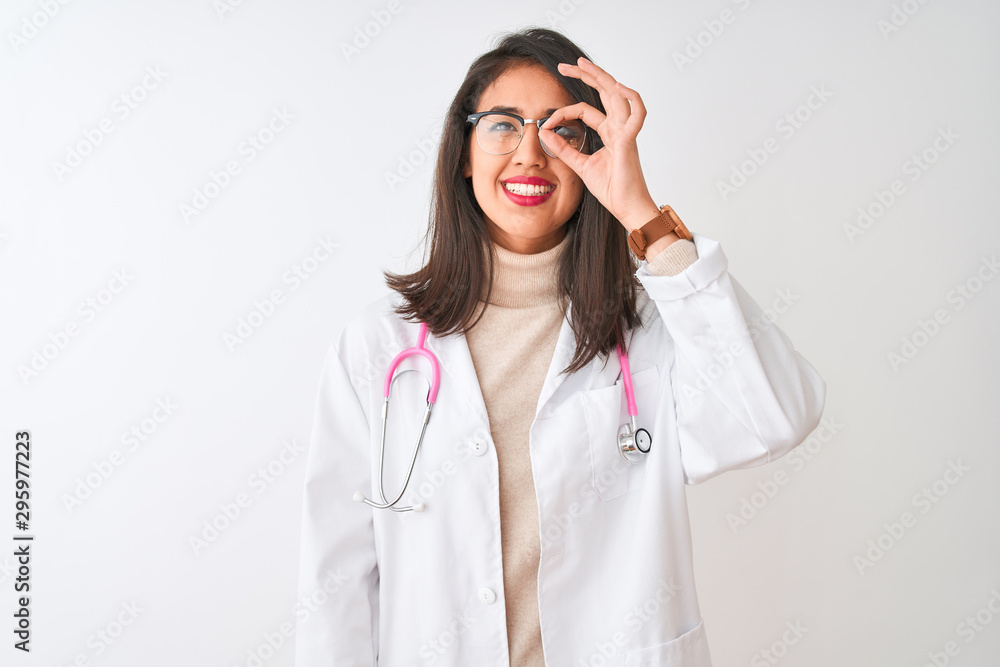 Chinese doctor woman wearing coat and pink stethoscope over isolated white background doing ok gesture with hand smiling, eye looking through fingers with happy face. Chinese doctor woman wearing coat and pink stethoscope over isolated white background doing ok gesture with hand smiling, eye looking through fingers with happy face.