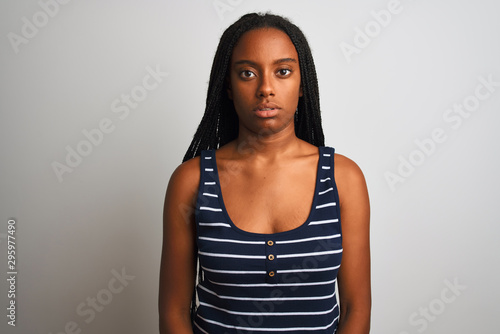 Young african american woman wearing striped t-shirt standing over isolated white background with serious expression on face. Simple and natural looking at the camera. © Krakenimages.com
