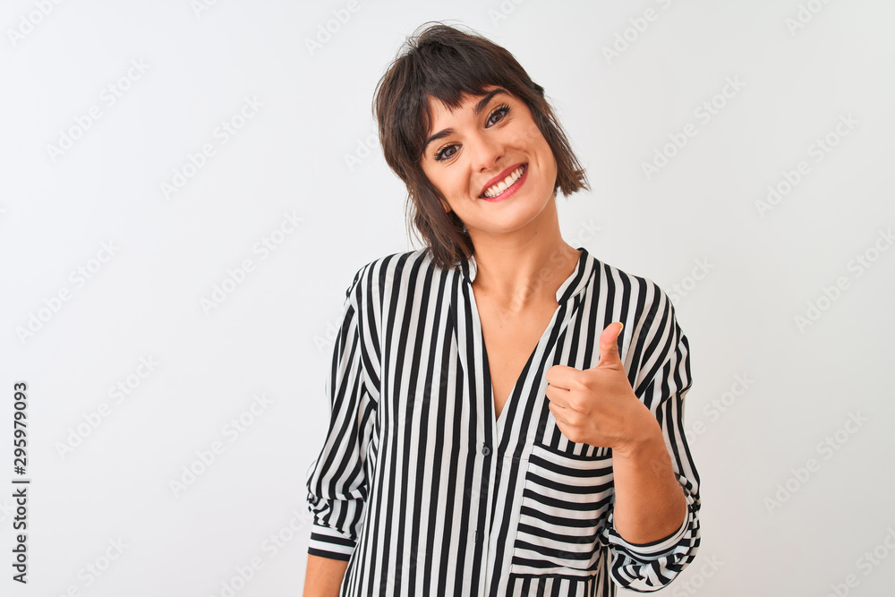Young beautiful woman wearing striped shirt standing over isolated white background doing happy thumbs up gesture with hand. Approving expression looking at the camera with showing success. Young beautiful woman wearing striped shirt standing over isolated white background doing happy thumbs up gesture with hand. Approving expression looking at the camera with showing success.