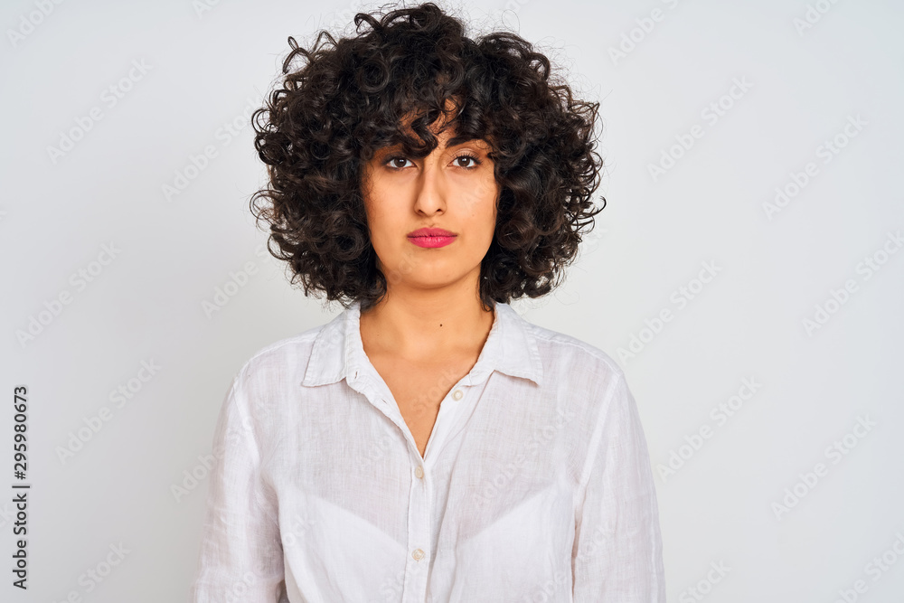 Young arab woman with curly hair wearing casual shirt over isolated white  background with serious expression on face. Simple and natural looking at  the camera. Stock Photo | Adobe Stock