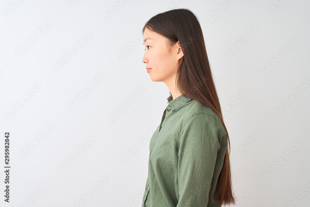 Young chinese woman wearing casual green shirt standing over isolated white background looking to side, relax profile pose with natural face with confident smile. Young chinese woman wearing casual green shirt standing over isolated white background looking to side, relax profile pose with natural face with confident smile.