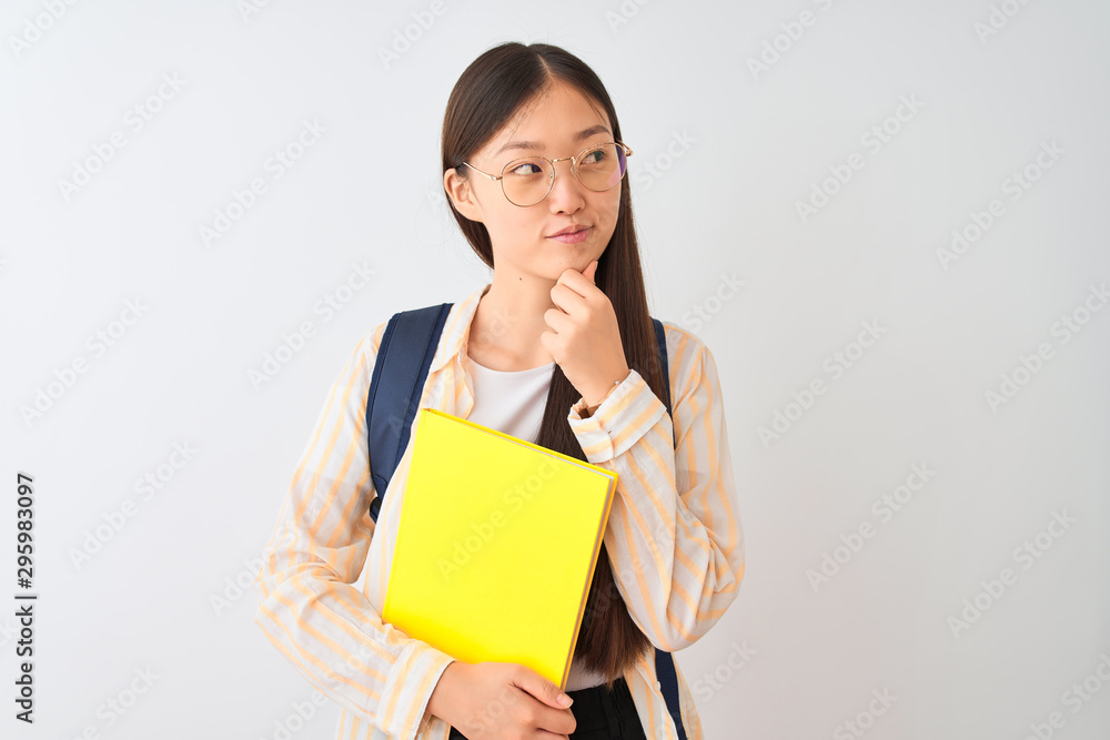 Chinese student woman wearing glasses backpack book over isolated white background serious face thinking about question, very confused idea Chinese student woman wearing glasses backpack book over isolated white background serious face thinking about question, very confused idea