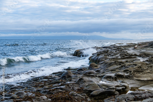 waves of waves pounding the rocky shore line on the island under overcast sky near dusk