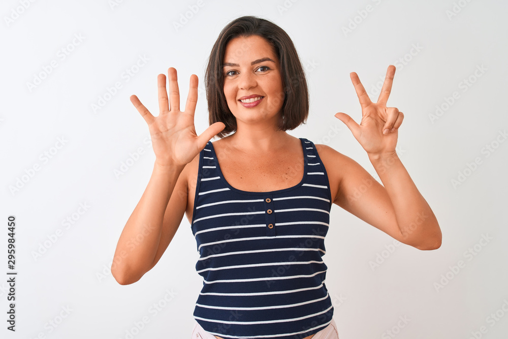 Young beautiful woman wearing blue striped t-shirt standing over isolated white background showing and pointing up with fingers number eight while smiling confident and happy. Young beautiful woman wearing blue striped t-shirt standing over isolated white background showing and pointing up with fingers number eight while smiling confident and happy.
