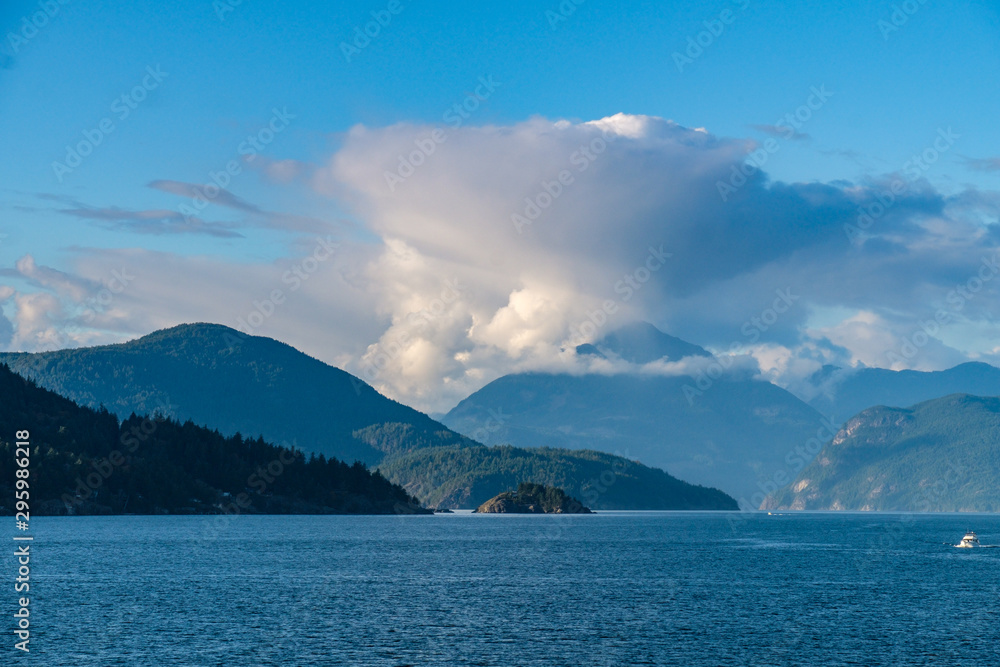 dense cloud with beautiful shape above the mountains of forest covered islands by the blue ocean on a sunny afternoon dense cloud with beautiful shape above the mountains of forest covered islands by the blue ocean on a sunny afternoon