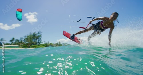 Young active woman riding by smiling kitesurfing in the ocean on a sunny day, fun times doing extreme sports