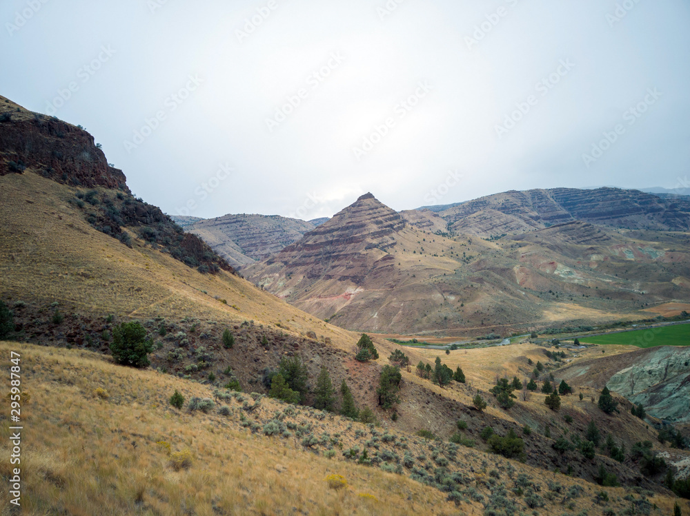 Breathtaking views of the grey-blue badlands and the scenic John Day River Valley and Mountains from the rustic Blue Basin Overlook Trail at the John Day Fossil Beds Sheep Rock Unit in Kimberly Oregon