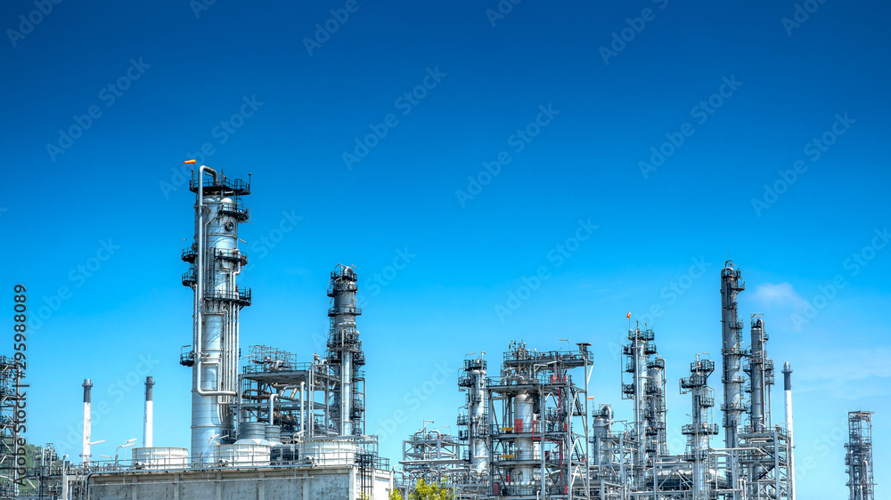 Fototapeta premium Oil and gas industrial refinery zone,Detail of equipment oil pipeline steel with valve from large oil storage tank at cloudy sky. -image