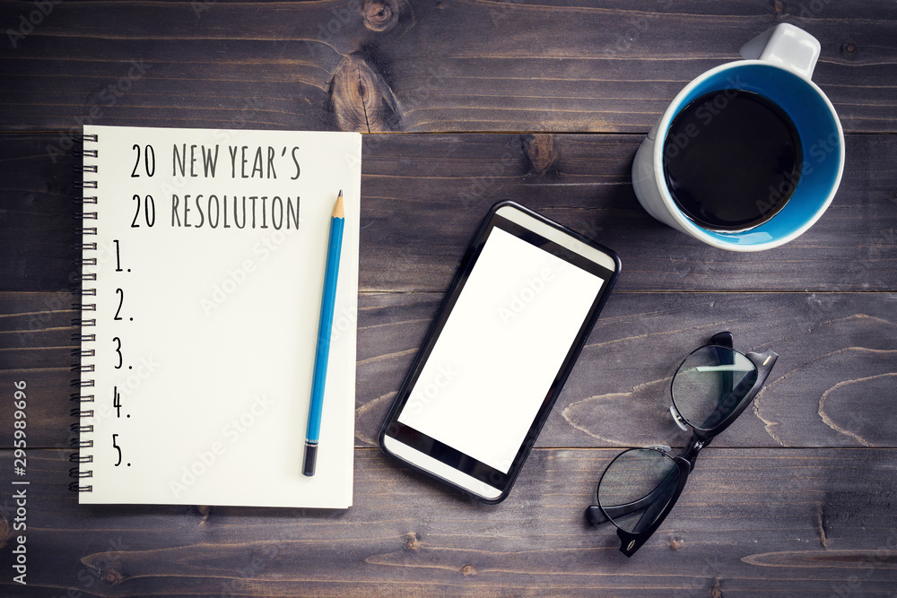 New Year goals, resolution or action plan 2020 concep. Office wood table with blank notepad, pencil, glasses, phone and cup of coffee. New Year goals, resolution or action plan 2020 concep. Office wood table with blank notepad, pencil, glasses, phone and cup of coffee.