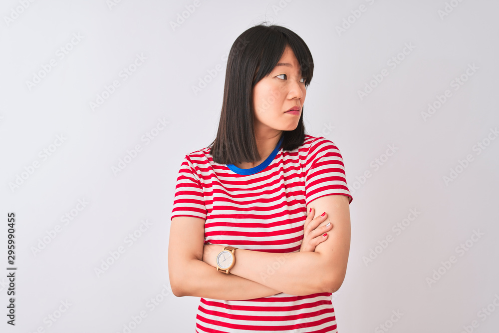 Young beautiful chinese woman wearing red striped t-shirt over isolated white background looking to the side with arms crossed convinced and confident Young beautiful chinese woman wearing red striped t-shirt over isolated white background looking to the side with arms crossed convinced and confident