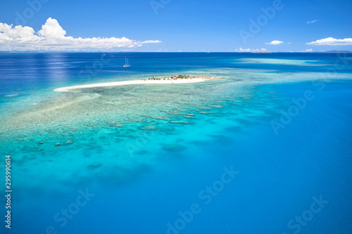 Person on remote island in Fiji overlooking blue coral reef photo