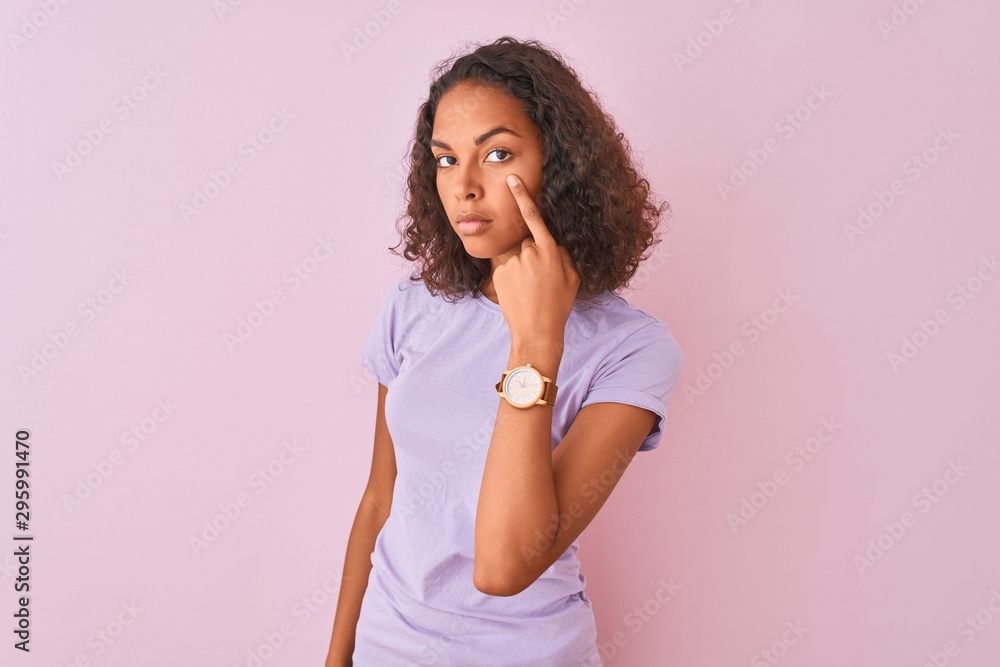 Young brazilian woman wearing t-shirt standing over isolated pink background Pointing to the eye watching you gesture, suspicious expression Young brazilian woman wearing t-shirt standing over isolated pink background Pointing to the eye watching you gesture, suspicious expression