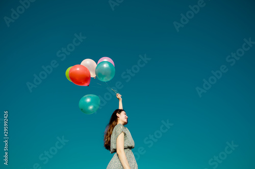 Happy asian woman playing colorful balloons on blue sky background. Freedom concept © Oulaphone