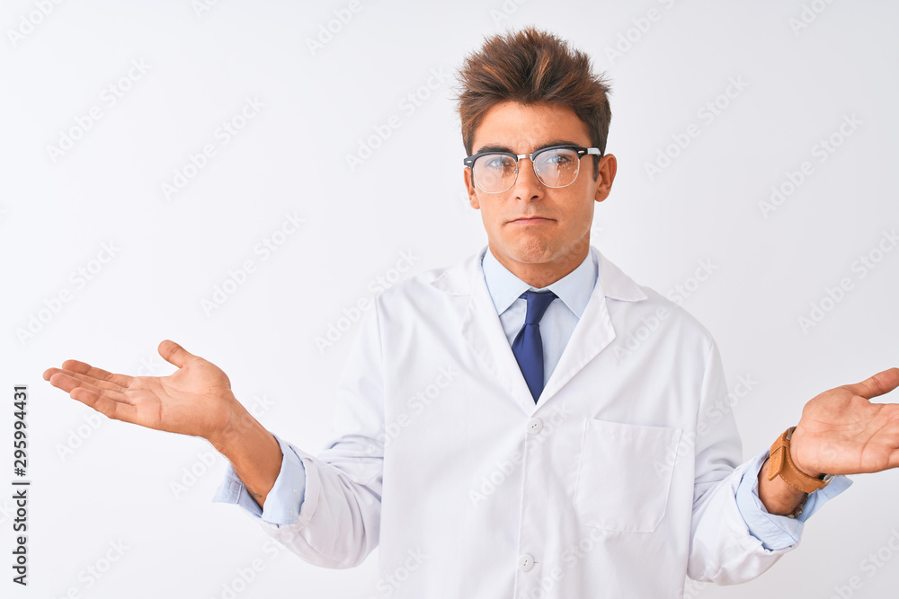 Young handsome sciencist man wearing glasses and coat over isolated white background clueless and confused expression with arms and hands raised. Doubt concept. Young handsome sciencist man wearing glasses and coat over isolated white background clueless and confused expression with arms and hands raised. Doubt concept.