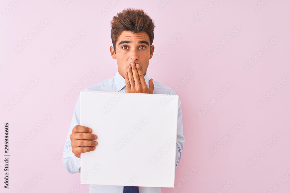 Young handsome businessman holding banner standing over isolated pink background cover mouth with hand shocked with shame for mistake, expression of fear, scared in silence, secret concept Young handsome businessman holding banner standing over isolated pink background cover mouth with hand shocked with shame for mistake, expression of fear, scared in silence, secret concept