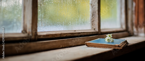 old books on the background of the village wooden wet window, copy space.