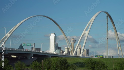 4K - The Dallas Skyline is Framed by the 2 Arches of the Margaret McDermott Bridge with the Iconic Reunion Tower in the center. Slow moving traffic drives over the bridge on a beautiful day. photo