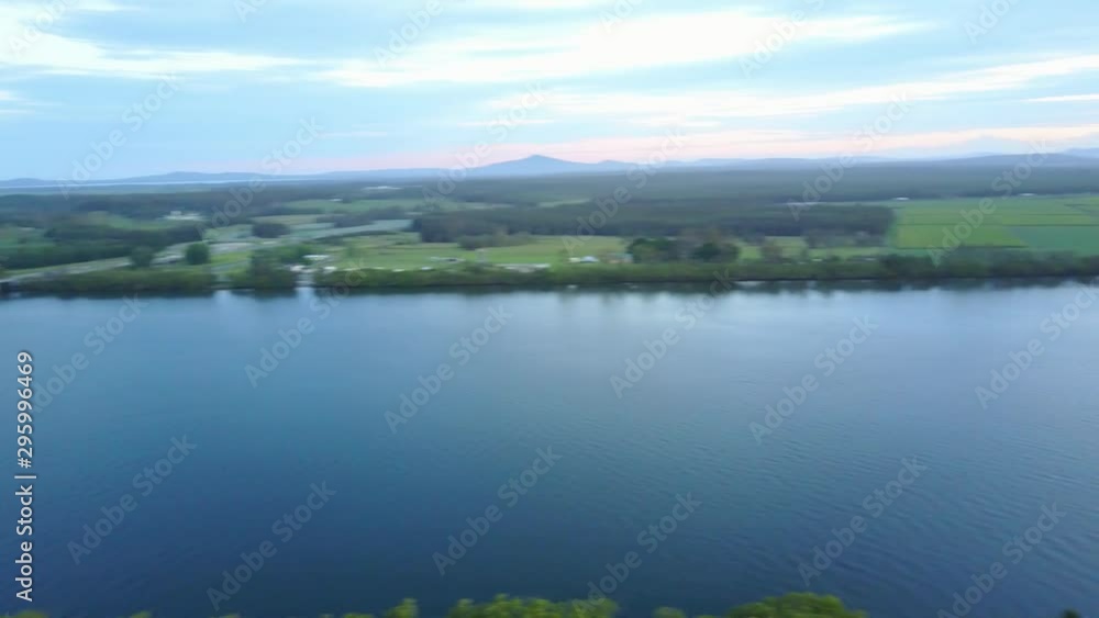 Aerial Drone Panning At Sunset Above Lush Farm Land With Corn Fields And Blue River Reflecting The Orange Sun Aerial Drone Panning At Sunset Above Lush Farm Land With Corn Fields And Blue River Reflecting The Orange Sun