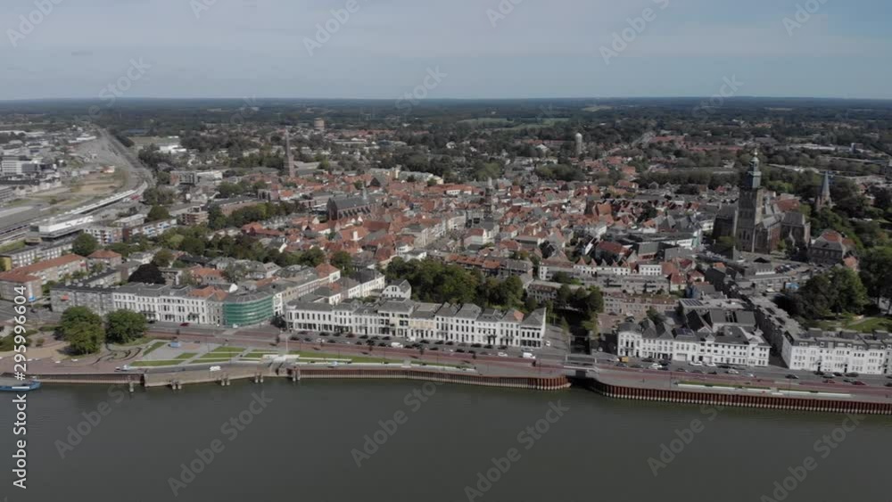 Aerial pan revealing the Hanseatic Dutch city of Zutphen from a distance. Cityscape of medieval town seen from above the river IJssel against a blue sky with white houses Aerial pan revealing the Hanseatic Dutch city of Zutphen from a distance. Cityscape of medieval town seen from above the river IJssel against a blue sky with white houses