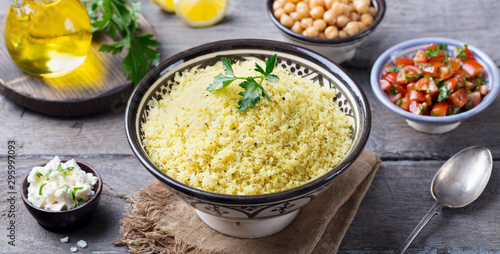 Couscous in bowl with olive oil. Wooden background. Close up.