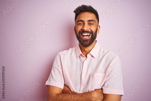 Young indian man wearing casual shirt standing over isolated pink background happy face smiling with crossed arms looking at the camera. Positive person.
