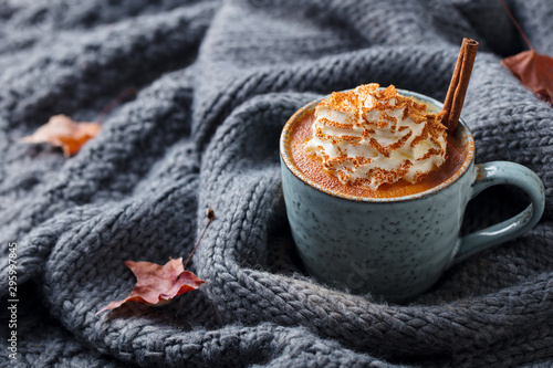 Fototapeta Naklejka Na Ścianę i Meble -  Pumpkin latte with spices and whipped cream. Grey knitted background. Copy space.