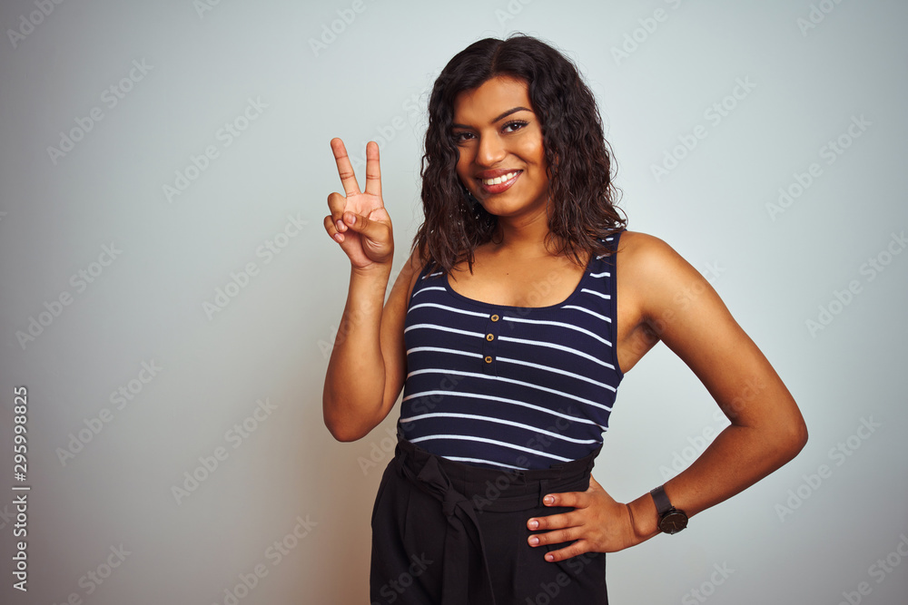 Transsexual transgender woman wearing striped t-shirt over isolated white background smiling looking to the camera showing fingers doing victory sign. Number two. Transsexual transgender woman wearing striped t-shirt over isolated white background smiling looking to the camera showing fingers doing victory sign. Number two.