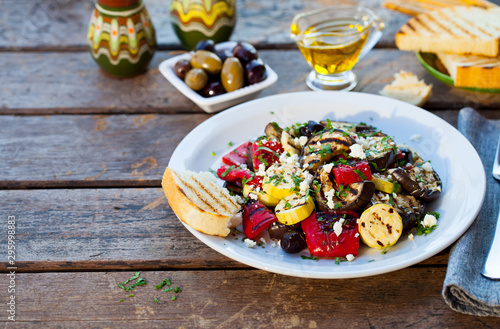 Grilled vegetables salad with feta cheese in white plate. Wooden background. Copy space.