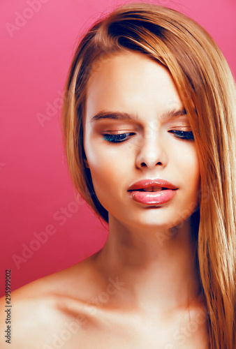 young pretty blonde real woman with hairstyle close up and makeup on pink background smiling, stylish fashion look like baby doll