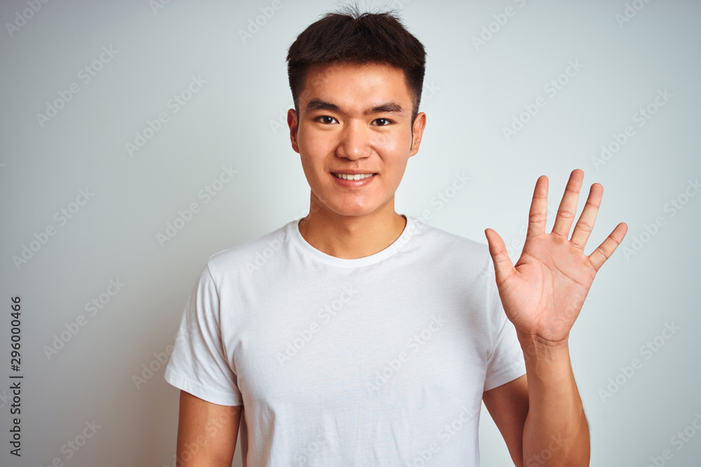 Young asian chinese man wearing t-shirt standing over isolated white background showing and pointing up with fingers number five while smiling confident and happy. Young asian chinese man wearing t-shirt standing over isolated white background showing and pointing up with fingers number five while smiling confident and happy.
