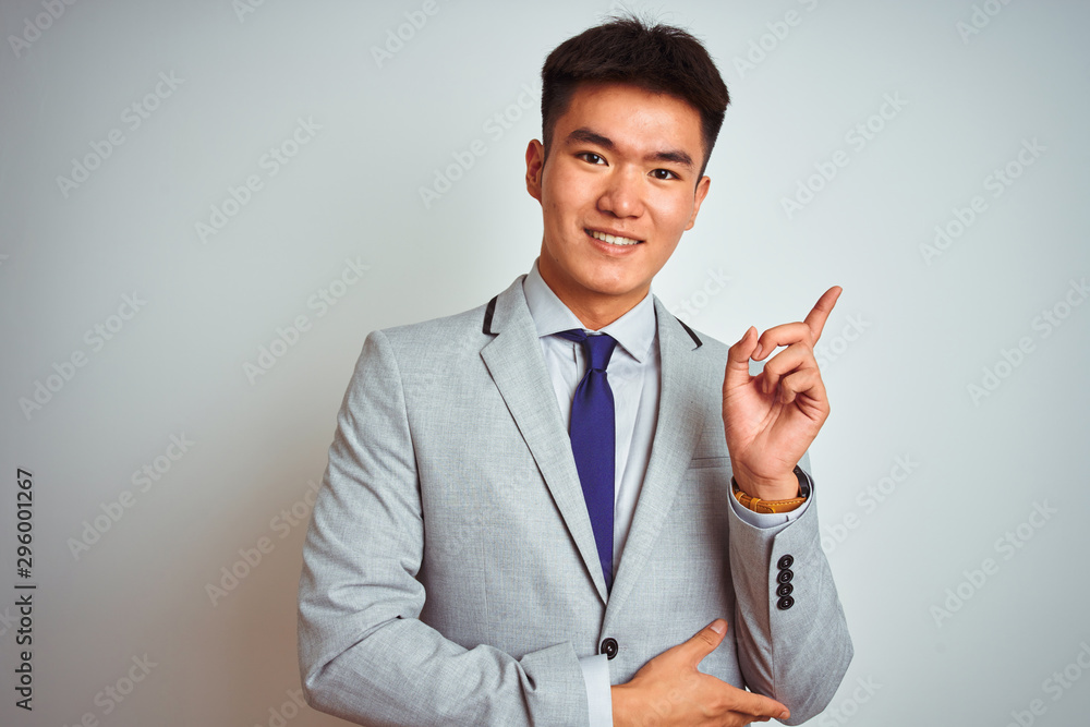 Asian chinese businessman wearing greyand tie standing over isolated white background with a big smile on face, pointing with hand and finger to the side looking at the camera. Asian chinese businessman wearing greyand tie standing over isolated white background with a big smile on face, pointing with hand and finger to the side looking at the camera.