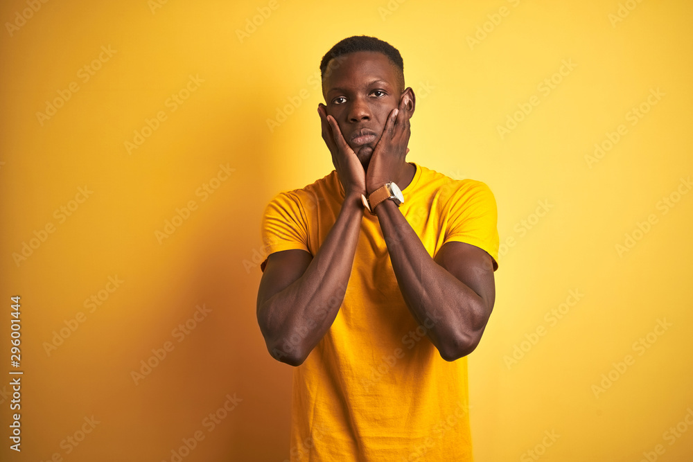 Young african american man wearing casual t-shirt standing over isolated yellow background Tired hands covering face, depression and sadness, upset and irritated for problem Young african american man wearing casual t-shirt standing over isolated yellow background Tired hands covering face, depression and sadness, upset and irritated for problem