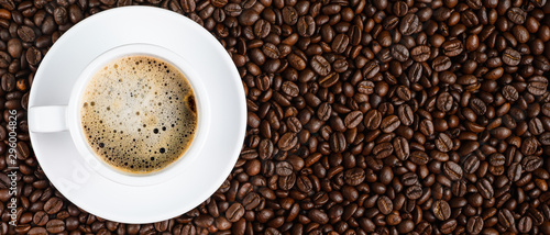 panoramic coffee background of a cup of black coffee covered with coffee bubble on roasted arabica coffee beans photo