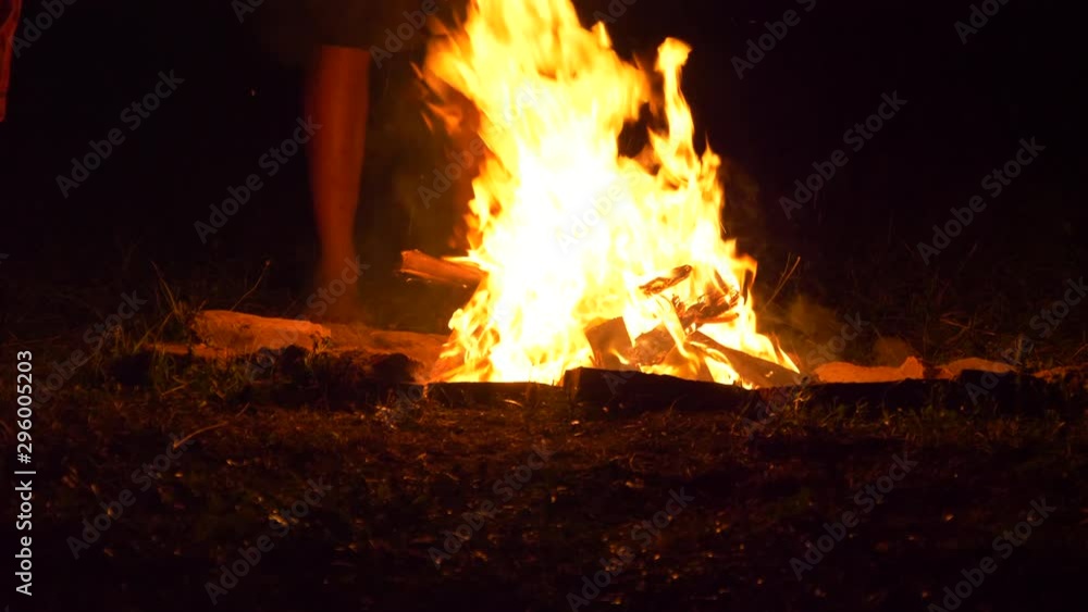 Man Leaps Over Glowing Bonfire At Night Barefoot, Others Standing By Man Leaps Over Glowing Bonfire At Night Barefoot, Others Standing By