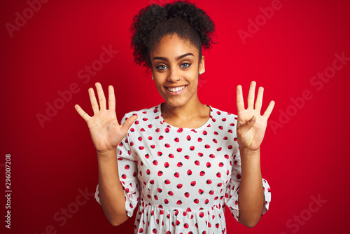 African american woman wearing fashion white dress standing over isolated red background showing and pointing up with fingers number nine while smiling confident and happy.