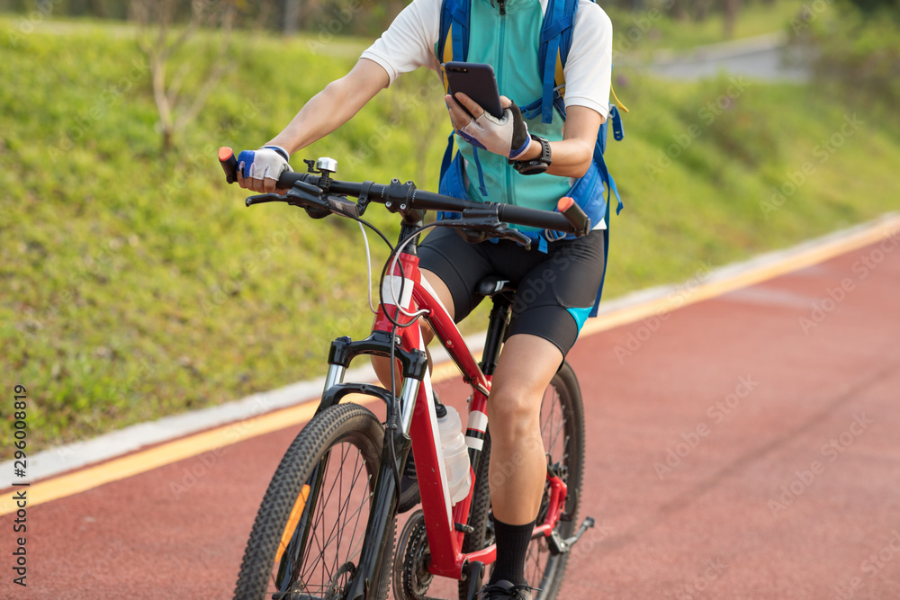 Riding on park bike path,using smartphone while riding bike on sunny day Riding on park bike path,using smartphone while riding bike on sunny day