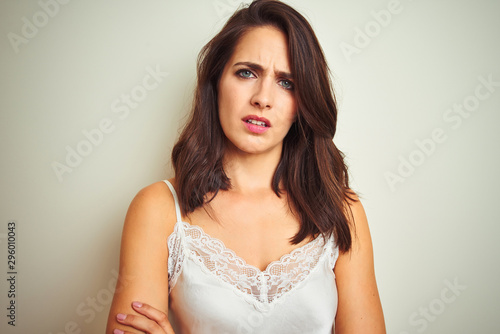 Young beautiful woman wearing t-shirt standing over white isolated background skeptic and nervous, disapproving expression on face with crossed arms. Negative person.