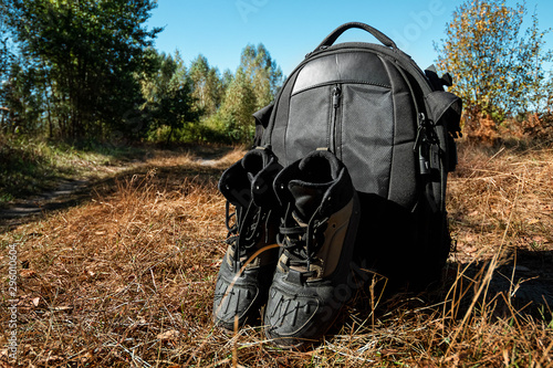 Camping backpack and boots on a background of summer nature. Trekking and camping adventures, hiking, hiking, traveling.