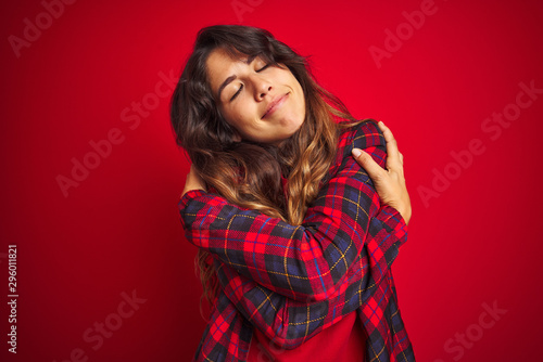 Young beautiful woman wearing casual jacket standing over red isolated background gesturing finger crossed smiling with hope and eyes closed. Luck and superstitious concept.