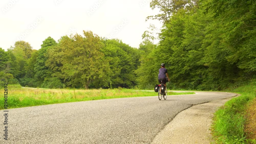 A man travelling with a touring bicycle through the forest road. A man travelling with a touring bicycle through the forest road.