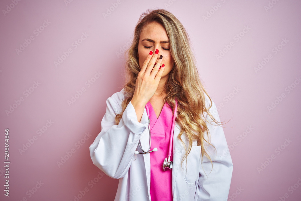 Young beautiful doctor woman using stethoscope over pink isolated background bored yawning tired covering mouth with hand. Restless and sleepiness.