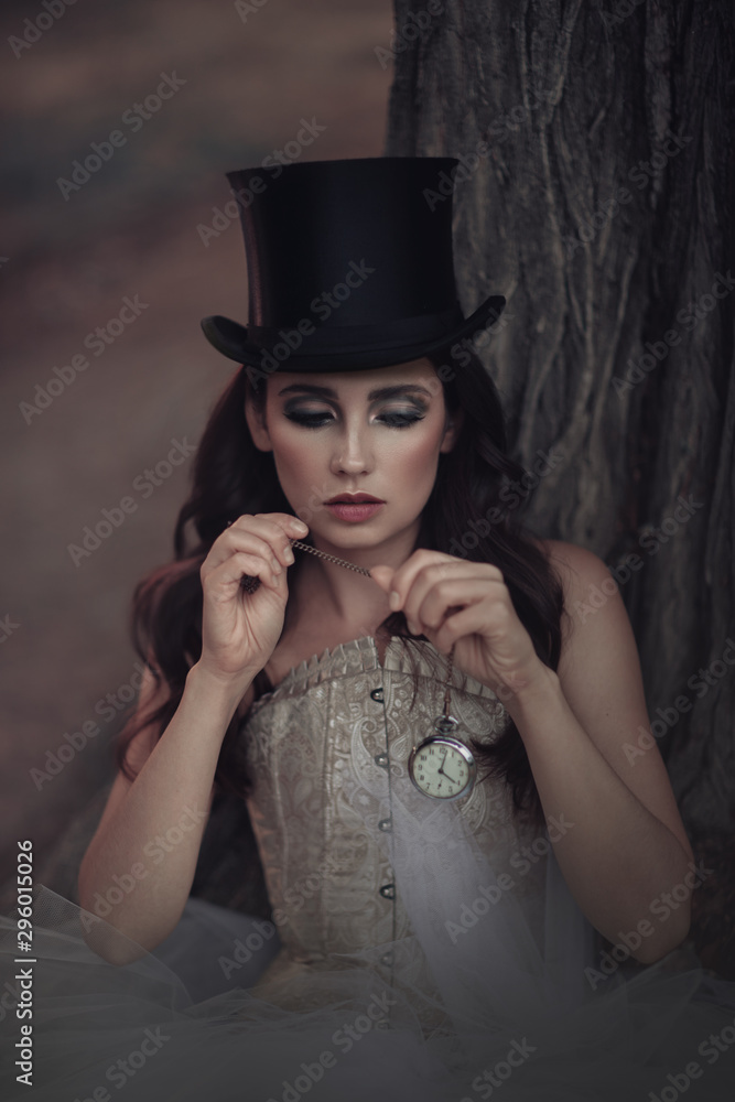Beautiful brunette in a vintage black top hat with a watch in hand.