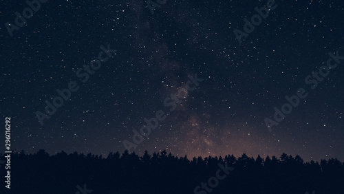 Milky way in the forest landscape affect the viewer's imagination, dense virgin forests on the slopes contribute to conceal the traces of civilization, illuminated Tent