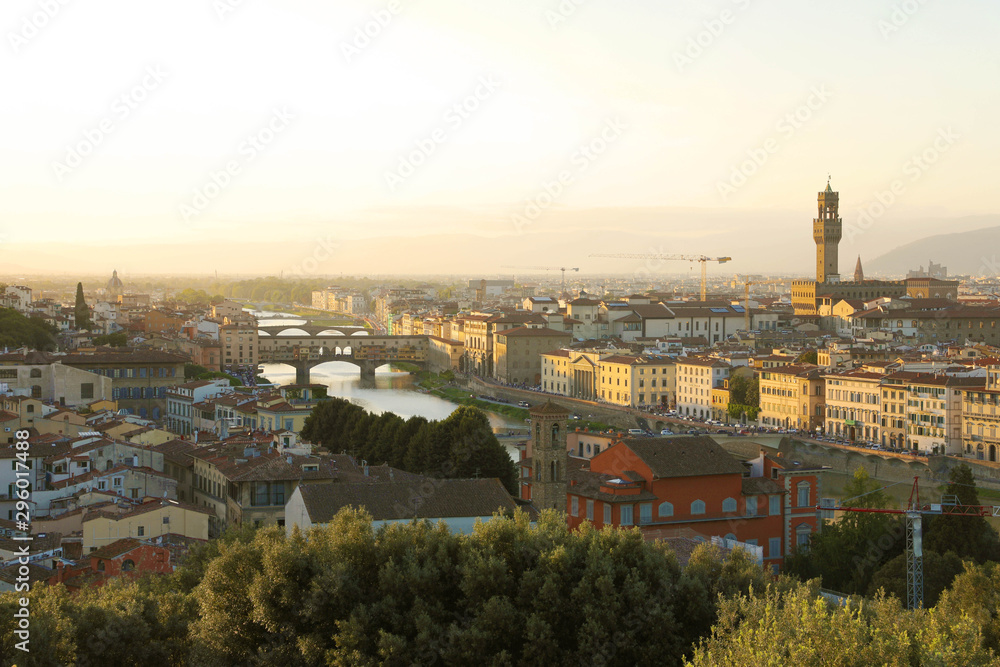 Florence city during golden sunset. Panoramic view of the river Arno with Ponte Vecchio bridge and Palazzo Vecchio palace, Florence, Italy.