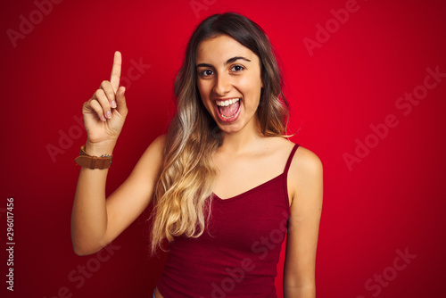 Young beautiful woman wearing a t-shirt over red isolated background pointing finger up with successful idea. Exited and happy. Number one.