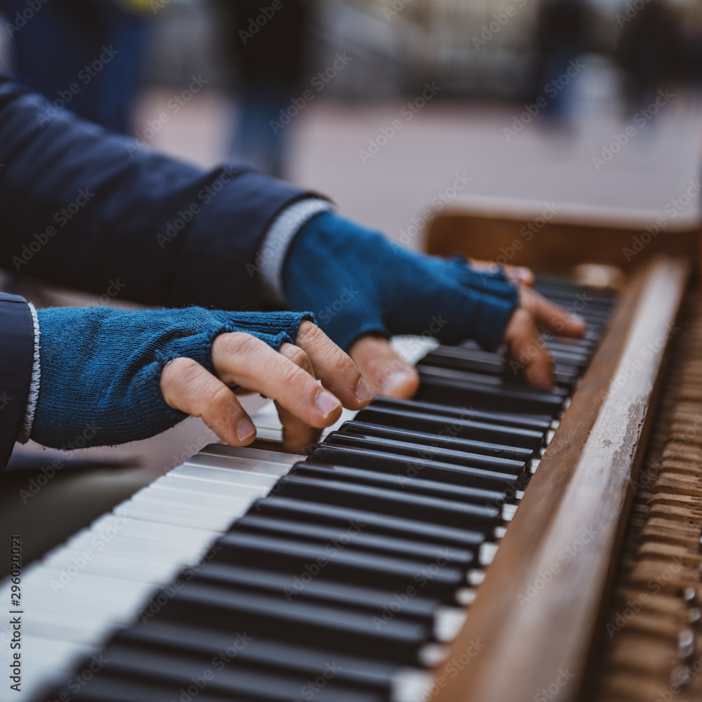 Man playing piano on the street in fingerless gloves