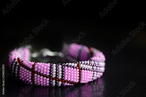 Pink bracelet made of seed beads on a dark background close-up